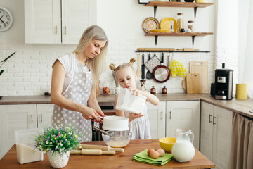 Cute little girl helps mom bake cookies in the kitchen