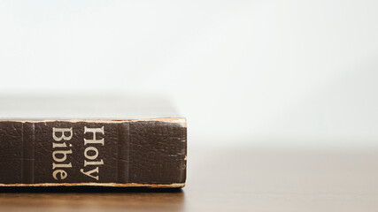 Holy Bible on wooden table against morning sunlight for prayer and bible study Christian devotion, copy space