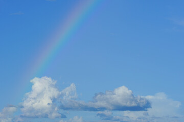 Naklejka na ściany i meble clear blue sky with cloudscape and rainbow crossing the sky
