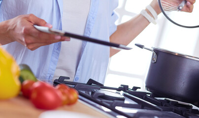 Young woman standing by the stove in the kitchen