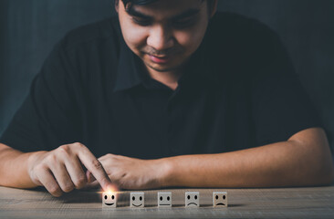 Hand of a businessman chooses a smiley face on wood block cube.Customer services best excellent business rating experience. Satisfaction survey concept.