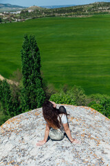 brunette woman sitting on a cliff looking at the nature of the journey