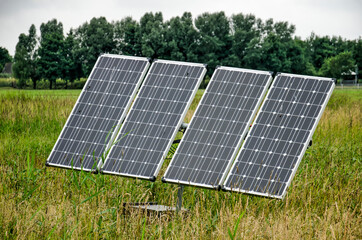 Maasland, The Netherlands, July 2, 2021: four solar panels placed in a green meadow in summer