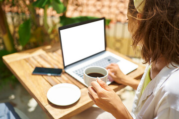 Rear view crop faceless female working on laptop computer with white empty screen. typing,...