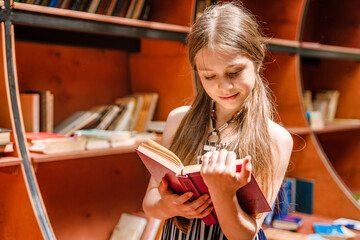 Cute little girl in the library in the park holding books. Togliatti, Russia - 29 May 2021