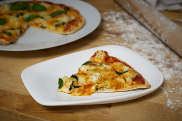 Homemade artisan pizza on white plate on wooden counter top