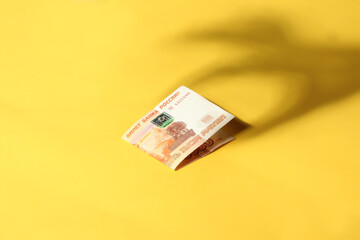 shadow of a hand and a bill on a yellow background
