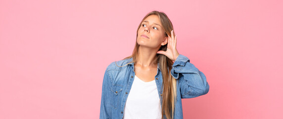 blonde pretty woman looking serious and curious, listening, trying to hear a secret conversation or...