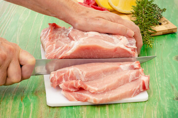 Manos con cuchillo cortando filetes de un trozo de carne fresca