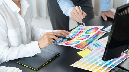 graphic designer team working on web design using color swatches editing artwork using tablet and a...