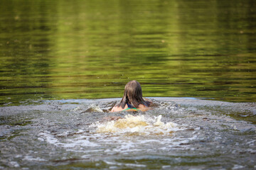 A girl swims in the river on a hot summer day