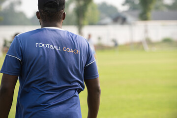 Fototapeta premium Football coach standing and watching his team on a sideline during a soccer match in a school tournament. Giving advices and encouragement is the key to success.