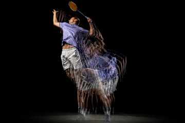 One young male badminton player, shuttler training isolated on dark background. Stroboscope effect.
