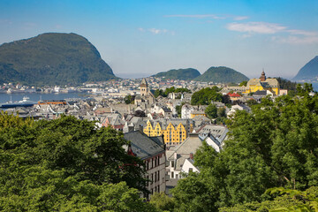 Fototapeta na wymiar View of Alesund; Panoramic view of the archipelago, the beautiful town centre with buildings surrounded by trees, art nouveau architecture and fjords from the viewpoint Aksla, Alesund, Norway.