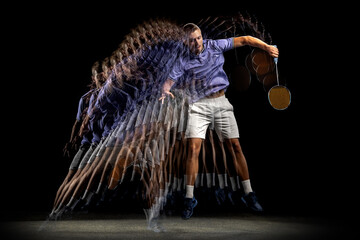 One young male badminton player, shuttler training isolated on dark background. Stroboscope effect.