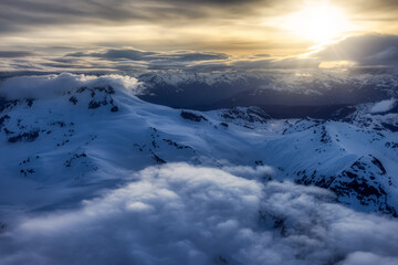 Fototapeta premium Aerial View from Airplane of Canadian Mountain Landscape in Spring time. Colorful Sunset Sky Artistic Render. North of Vancouver, British Columbia, Canada.