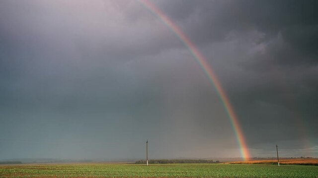 Dramatic Sky During Rain With Rainbow On Horizon Above Rural Landscape Field. Agricultural And Weather Forecast Concept. Time Lapse, Timelapse, Time-lapse. Countryside Meadow In Autumn Rainy Day