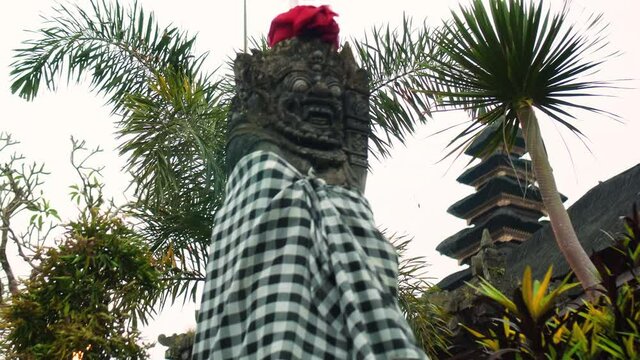old Indonesian ethnic stone statue of an evil demon with an open mouth and fangs covered with cloth
