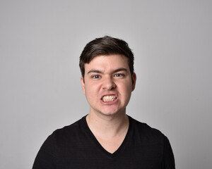 Obraz premium Close up head and shoulders portrait of a brunette. young man with a variety of expressive facial expressions. Isolated on a light grey studio background.