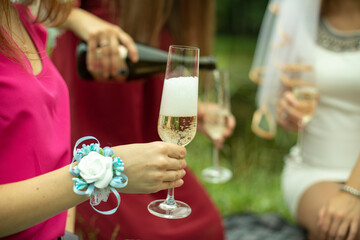 The girl pours wine into a glass. Girls at a picnic.