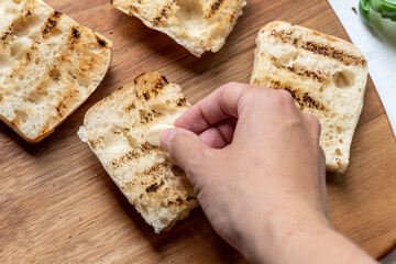 Hand rubbing fresh garlic on toasted bread