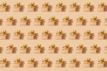 Pattern of golden holiday boxes with ribbon on a yellow background. Festive pattern background.