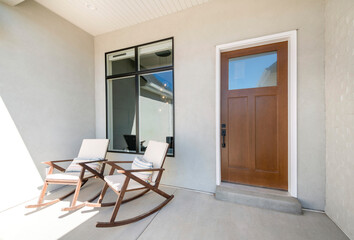 Front porch with two rocking chairs and wooden door with glass panel