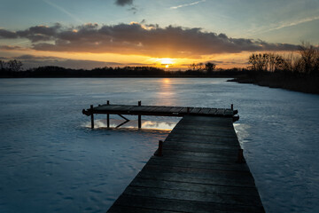 A pier on a frozen lake and a beautiful sunset