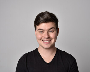 Close up head and shoulders portrait of a brunette. young man with a variety of expressive facial expressions. Isolated on a light grey studio background.