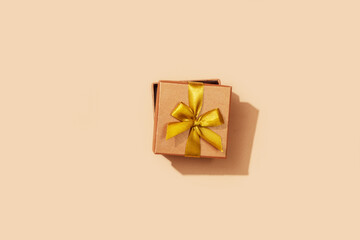Gold festive box with ribbon on a yellow background. Festive background.