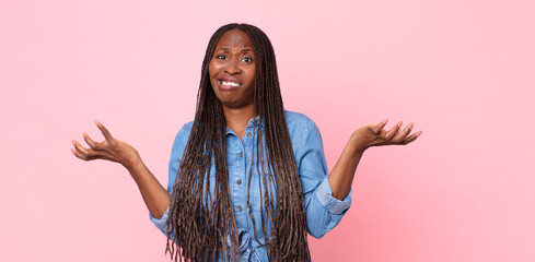 afro black adult woman shrugging with a dumb, crazy, confused, puzzled expression, feeling annoyed...