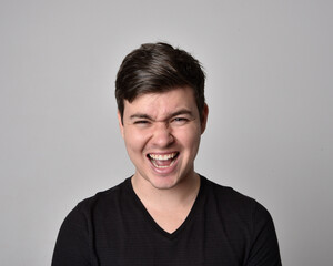 Fototapeta premium Close up head and shoulders portrait of a brunette. young man with a variety of expressive facial expressions. Isolated on a light grey studio background.