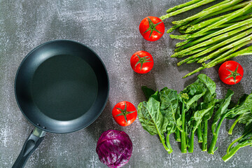 pan and various vegetables,Assortment of fresh organic ingredients for cooking pasta and black empty pan on dark stone background. Healthy food concept. Long banner format. Culinary blog template.