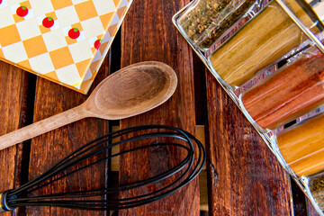 Kitchen utensils. Cookbook, spices, wooden spoon and fouet.