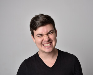 Fototapeta premium Close up head and shoulders portrait of a brunette. young man with a variety of expressive facial expressions. Isolated on a light grey studio background.