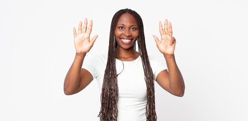 afro black adult woman smiling and looking friendly, showing number nine or ninth with hand...