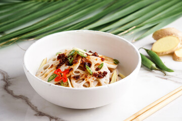 spicy lotus root salad on the white stone background, asian food 
