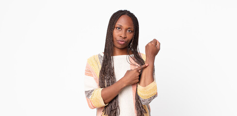 afro black adult woman looking impatient and angry, pointing at watch, asking for punctuality,...