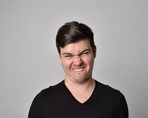 Close up head and shoulders portrait of a brunette. young man with a variety of expressive facial expressions. Isolated on a light grey studio background.