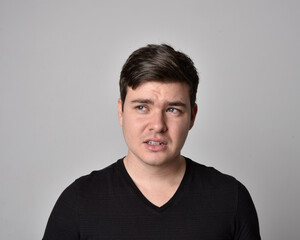 Close up head and shoulders portrait of a brunette. young man with a variety of expressive facial expressions. Isolated on a light grey studio background.