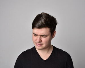Close up head and shoulders portrait of a brunette. young man with a variety of expressive facial expressions. Isolated on a light grey studio background.