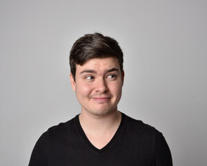 Fototapeta premium Close up head and shoulders portrait of a brunette. young man with a variety of expressive facial expressions. Isolated on a light grey studio background.