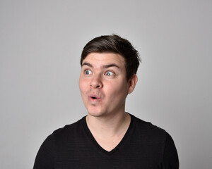 Fototapeta premium Close up head and shoulders portrait of a brunette. young man with a variety of expressive facial expressions. Isolated on a light grey studio background.