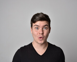 Close up head and shoulders portrait of a brunette. young man with a variety of expressive facial expressions. Isolated on a light grey studio background.