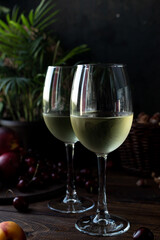 White wine is poured into glasses. There are fruits nearby