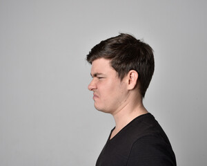 Obraz premium Close up head and shoulders portrait of a brunette. young man with a variety of expressive facial expressions. Isolated on a light grey studio background.