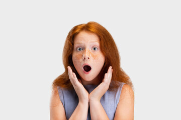 Portrait of cute freckled red-headed girl in casual outfit posing isolated on white studio...