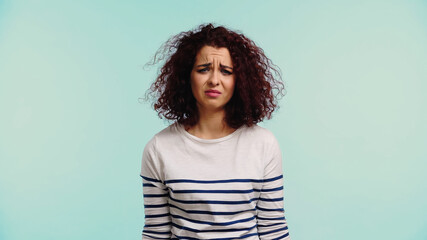 Fototapeta premium upset young woman in striped long sleeve shirt isolated on blue