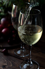 White wine is poured into glasses. There are fruits nearby