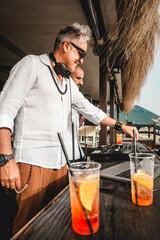 Disc jockeys playing music for tourist people at club party outdoors on the beach - Djs wearing...